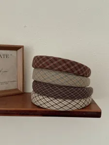 Détail rapproché de quatre serre-têtes rétro à carreaux empilés au design couronne haute.