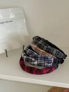 Stapel stylischer karierter geflochtener schmaler Stirnbänder in verschiedenen Farben.