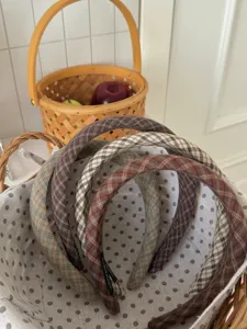 Détail de serre-têtes vintage à carreaux présentés dans un panier en osier rustique