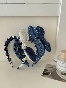 Three denim polka dot headbands with rabbit ear bows on a clean white shelf
