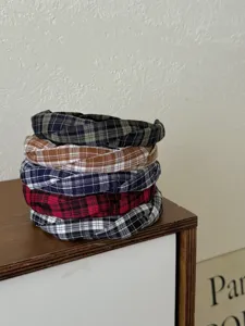 Stapel von fünf bunten geflochtenen Stirnbändern mit Karomuster auf einem Holzmöbel