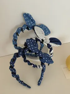 Close-up of three blue polka dot denim bow headbands stacked on a neutral background