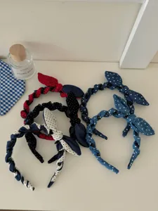 Assorted denim polka dot bow headbands displayed on a white surface with props