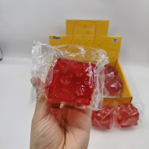 Macro view of a red square squishy stress relief toy held in hand with clear packaging