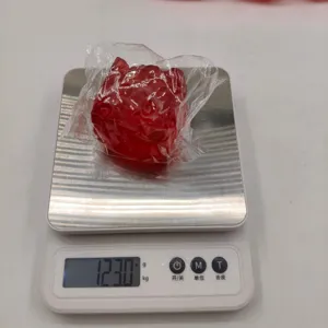 Detail view of a red ice cube squishy toy weight measurement on a scale at 123.0 grams