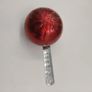 Balle anti-stress de Noël rouge scintillante mesurée avec une règle en métal argenté