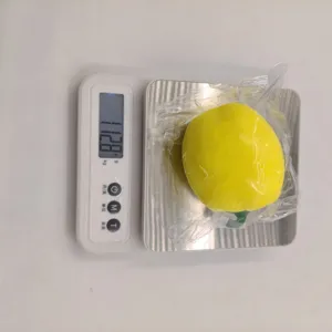 Gewichtsmeting van gele paprika stress speelgoed toont 112,8 gram op digitale weegschaal
