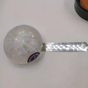 Halloween 8.5cm glitter jelly squishy toy with eyeball design being measured by ruler