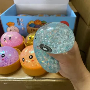 Hand die een schattig smiley gezicht bun squishy stressspeelgoed met glitterkralen indrukt.