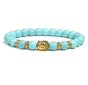 Close-up detail of turquoise bead bracelet featuring golden Buddha head and metal spacers.