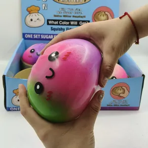 Close-up of hands squeezing a large pink and green gradient cute baozi squishy toy