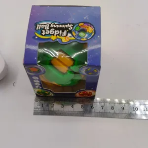 Größenreferenz des grünen und gelben Fidget Spinning Ball Spielzeugs in der Originalverpackung
