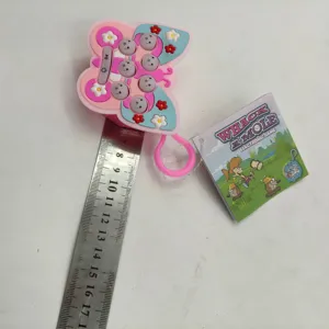 Close-up of pink butterfly Whack-a-Mole keychain game with size reference ruler.