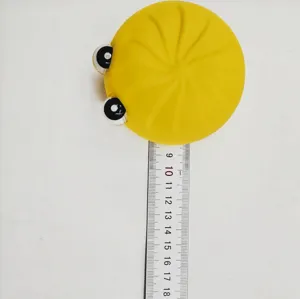 Juguete antiestrés con forma de bollo amarillo medido con una regla de plástico