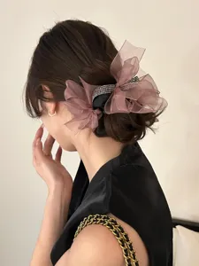 Elegante mauve organza strik scrunchie met glinsterende strass op een lage knot kapsel