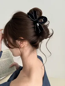 Detail of a black velvet bow hair claw clip with dotted trim in a bun hairstyle