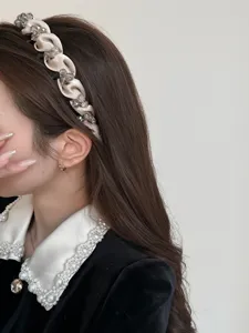 Nahaufnahme eines eleganten champagnerfarbenen Satin-Haarreifs mit Kristallverzierungen