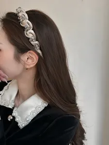 Detailansicht eines luxuriösen Satin-Haarreifs mit grauen Kristallen auf dunklem Haar