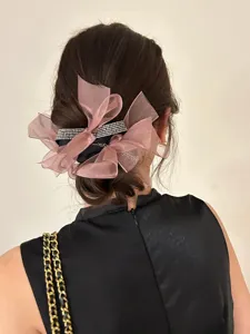 Gedetailleerde weergave van een roze mesh bow scrunchie met sprankelende strass-steentjes