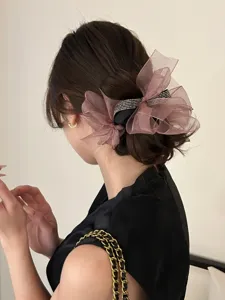 Elegante mauve organza strik scrunchie met strasstenen gedragen op een lage knot haarstijl