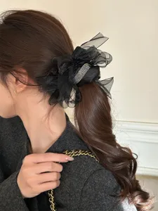 Detailopname van een elegante zwarte mesh strik scrunchie met strass op een paardenstaart