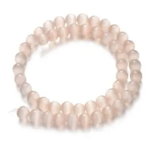 Close-up of light pink cat eye stone loose beads, round drilled DIY bracelet accessories detail.