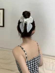 Elegant sheer white mesh bow hair claw clip shown worn in a high bun back view