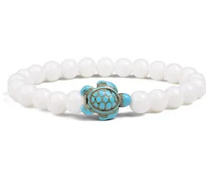 Detailed view of white beaded bracelet featuring a turquoise turtle charm centerpiece.