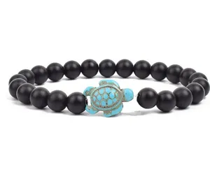 Close-up detail shot of black matte beaded bracelet featuring a turquoise turtle charm.