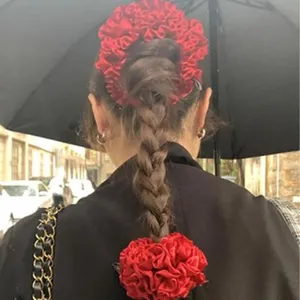 Back view of a red oversized lace scrunchie styled in a braided ponytail.