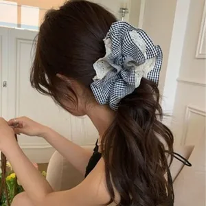 Rear view of a model wearing an oversized black and white gingham lace hair scrunchie