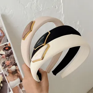 Detailansicht der stilvollen, gepolsterten Haarreifen mit goldenen Fashion-Logos