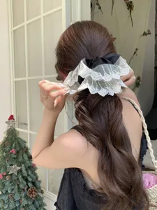 Close-up detail of black and white lace mesh scrunchie worn on long wavy brown hair