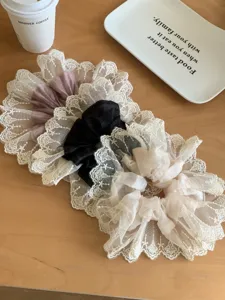 Set of three elegant lace mesh scrunchies in pink, black and cream on a wooden table