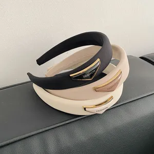 Nahaufnahme von drei breiten Schwamm-Stirnbändern in verschiedenen Farben mit modischen Logo-Platten
