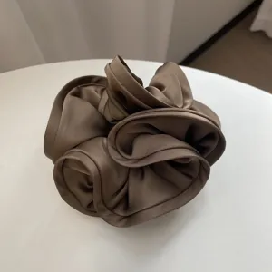 Détail rapproché d'un chouchou en satin marron café avec d'élégants bords ondulés.
