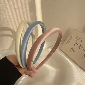 Detalle de tres diademas de satén estilo francés en amarillo, azul y rosa pastel