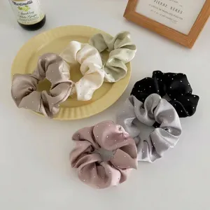 Close-up of elegant rhinestone scrunchies in various soft colors for hair styling.