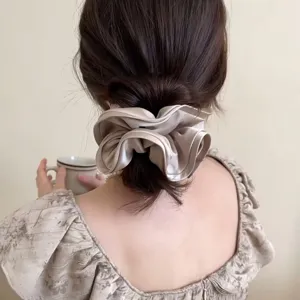 Chouchou élégant en satin champagne avec bords plissés sur une coiffure en chignon
