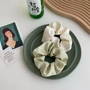 Close-up of elegant satin scrunchies with sparkling rhinestone studs in cream and sage green