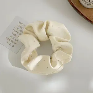 Close-up of cream satin scrunchie adorned with shimmering rhinestones