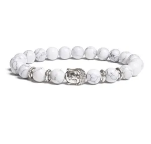 Close-up detail of the white beaded bracelet featuring a silver Buddha head and metal spacers.