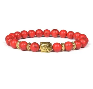 Detailed shot of red stone beaded bracelet with golden Buddha head and metal spacers.