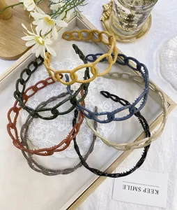 Detail view of various candy-colored chain-link plastic headbands in an aesthetic tray