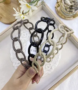 Close-up detail of glossy plastic chain link headbands in brown, black, and beige.