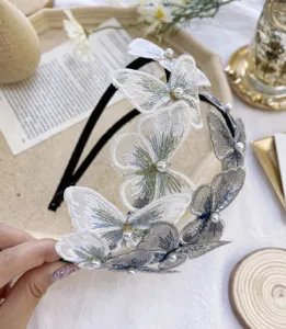 Detalle del bordado de mariposa blanca y azul con perlas en una diadema fina y elegante.