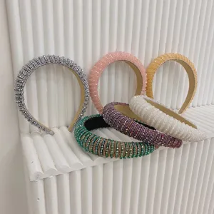 Assorted baroque crystal beaded headbands displayed on a stylish white ribbed stand