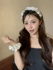 Primer plano de una modelo con una elegante diadema blanca con pedrería y un coletero
