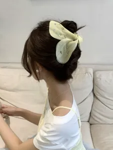Large sheer tulle bow hair claw clip with star rhinestones worn on a bun hairstyle