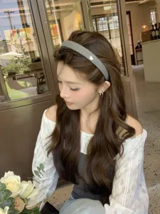 Elegant gray fabric headband with small heart detail worn by a model in a cafe